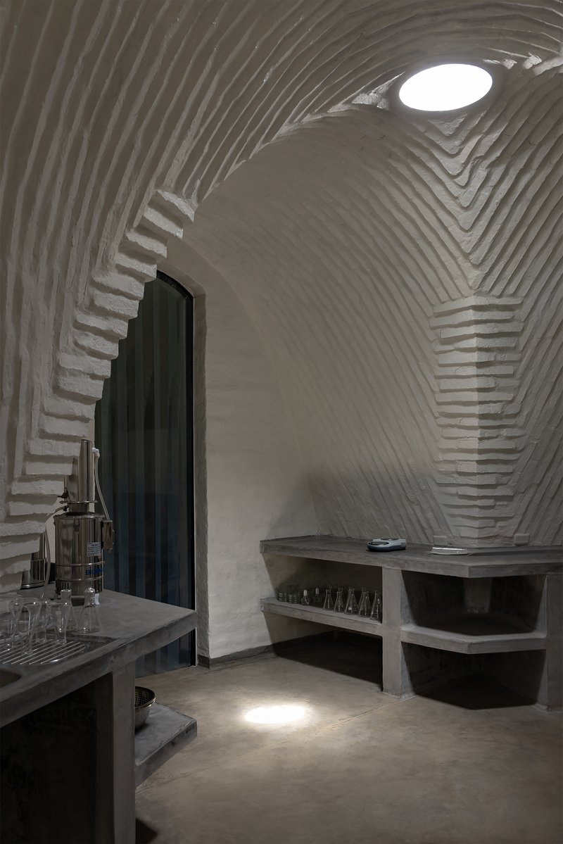 Arched doorway with black curtain beneath ribbed vault alongside concrete work counter and equipment
