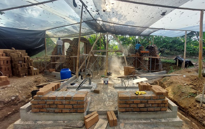 Brick walls rising on foundation under temporary scaffolding with workers on site