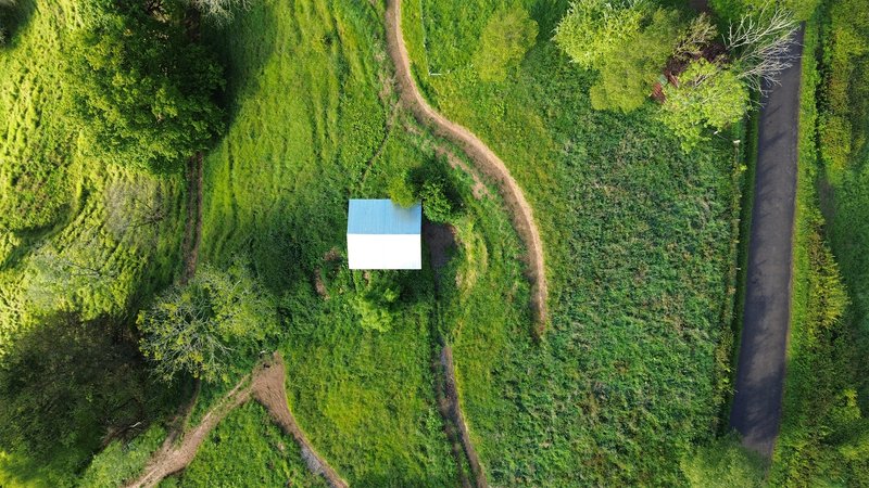 Aerial view of the white metal roof surrounded by terraced agricultural fields and winding dirt paths