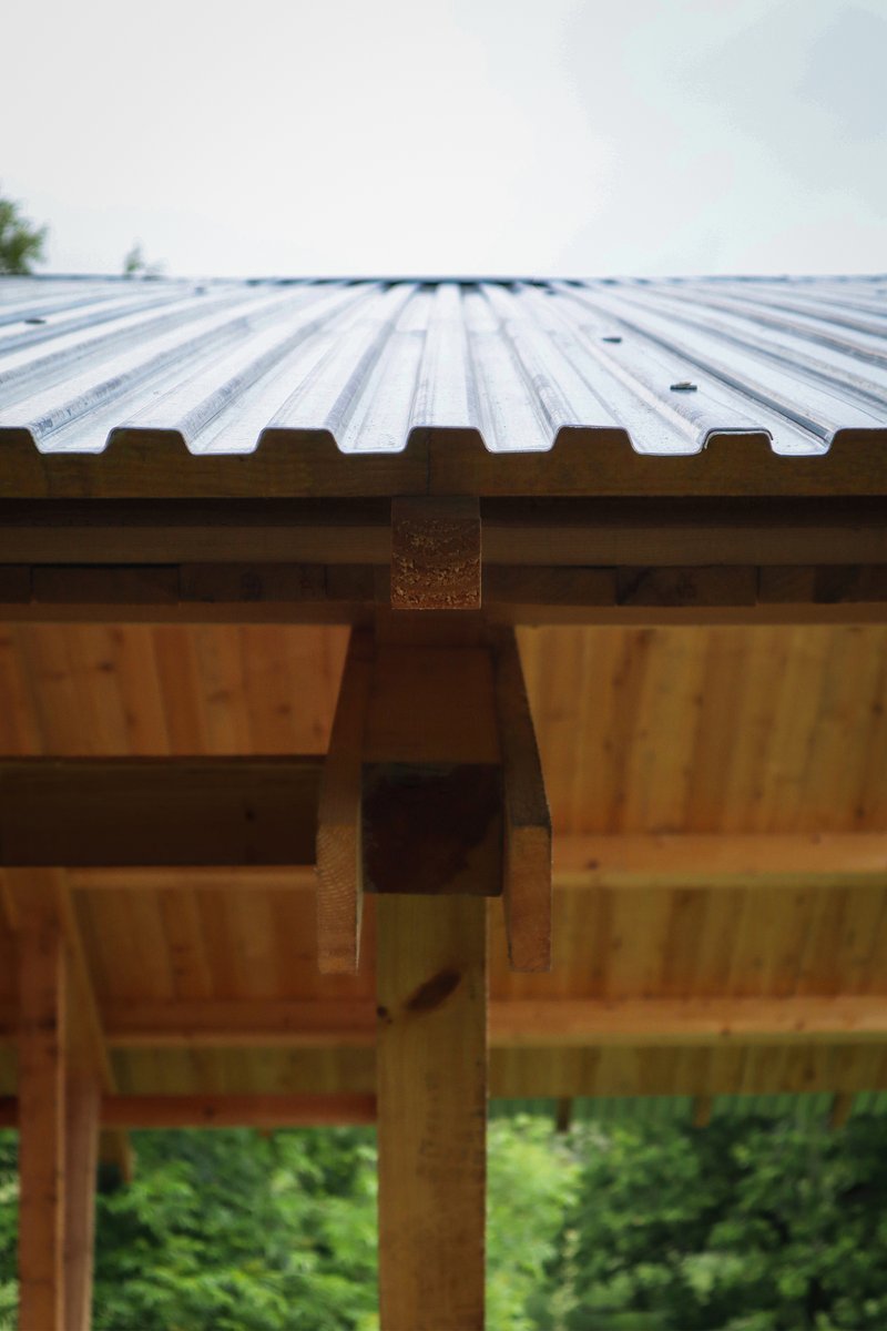 Detail of the corrugated metal roofing meeting the laminated timber beams and structural joinery