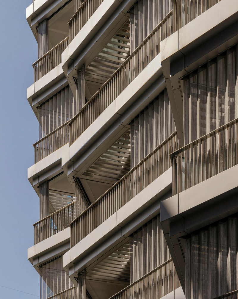 Facade detail showing stacked balconies with vertical timber screening and projecting concrete floor slabs