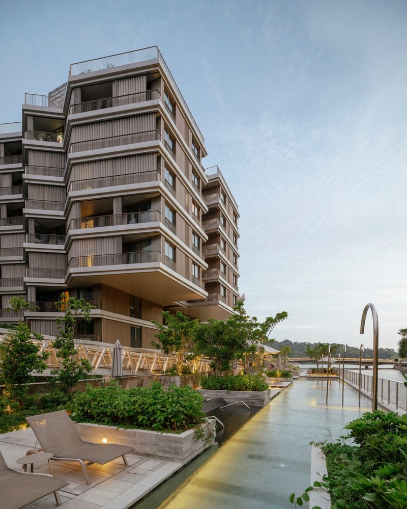 Rooftop pool deck with planted beds and residential towers rising above at twilight