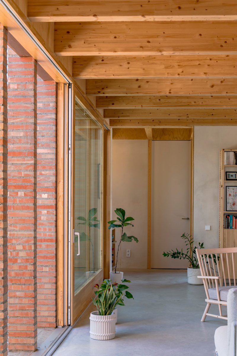 Interior hallway with exposed timber ceiling joists and sliding glass doors beside perforated brickwork