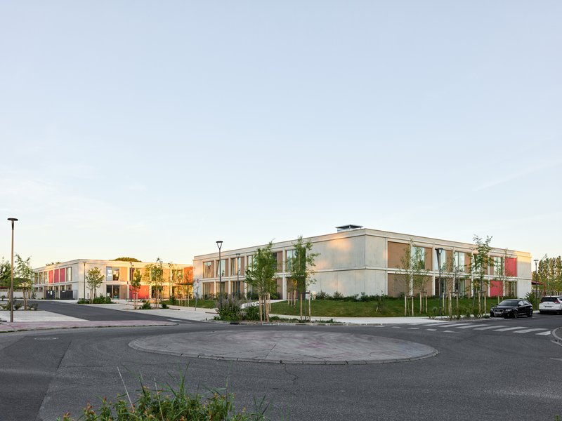 Corner view of the two-story school building complex from the access road at sunset