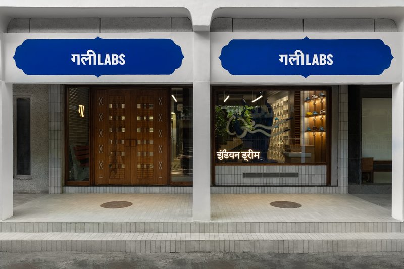 Street-facing storefront with timber screens, signage, and display windows at dusk