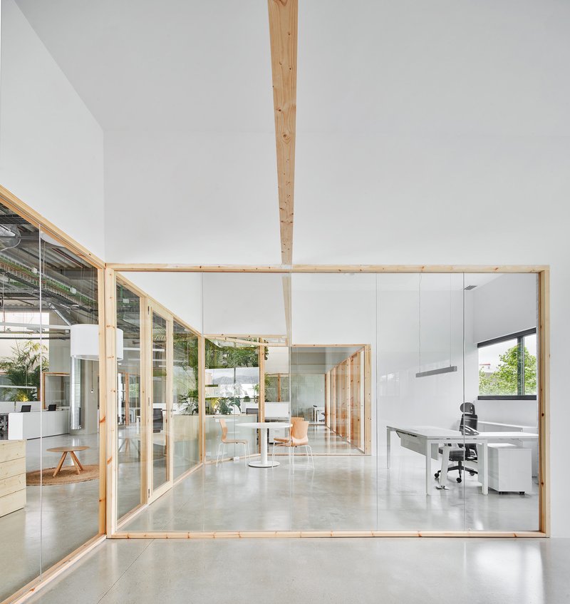 Glass-walled office enclosure with timber frame and central wood column on polished concrete floor