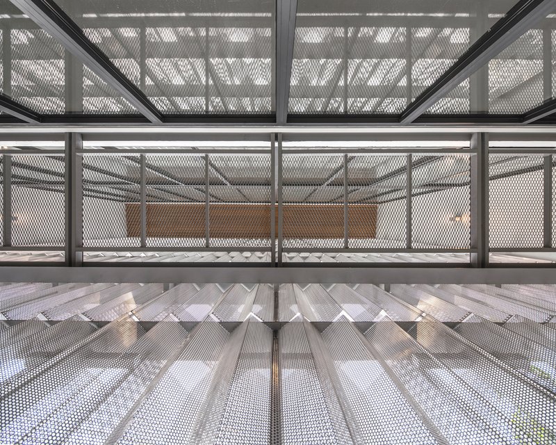 Looking up through stairwell clad in perforated metal mesh with zigzag folded underside