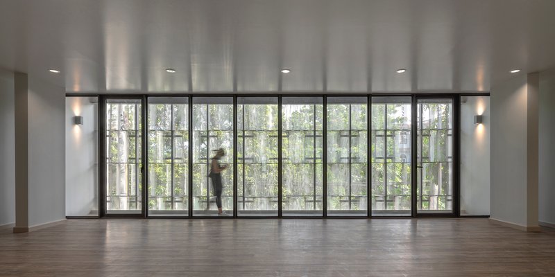 Interior room with floor-to-ceiling glazed doors opening to a balcony with trees beyond