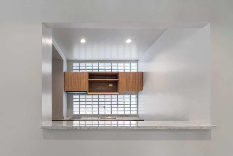 Kitchen pass-through with timber cabinetry and glass block windows above and below the counter