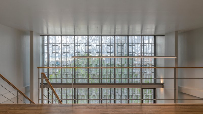 Interior stairwell landing facing gridded window wall with diagonal muntins and overcast daylight
