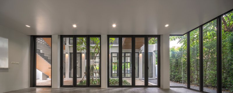 Interior space with folding glass doors surrounding courtyard gardens with mature trees