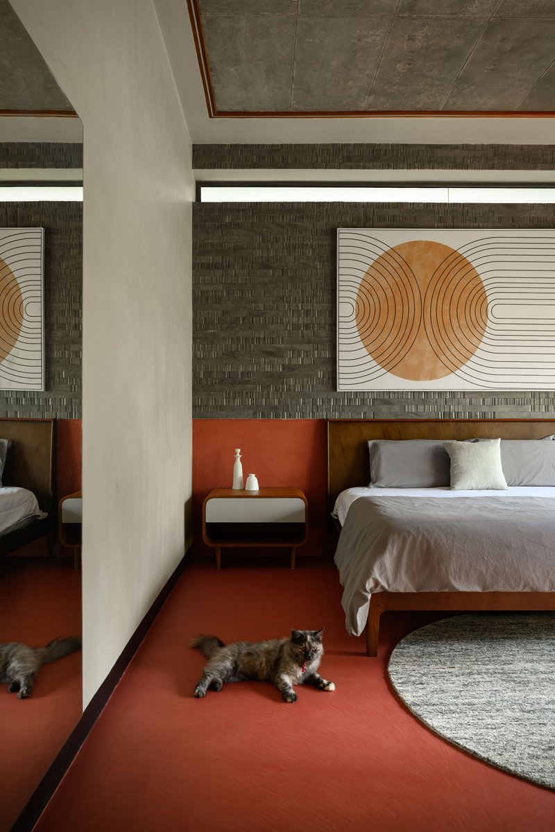 Double bedroom suite with white column divider, terracotta floor, and two cats resting on a round rug