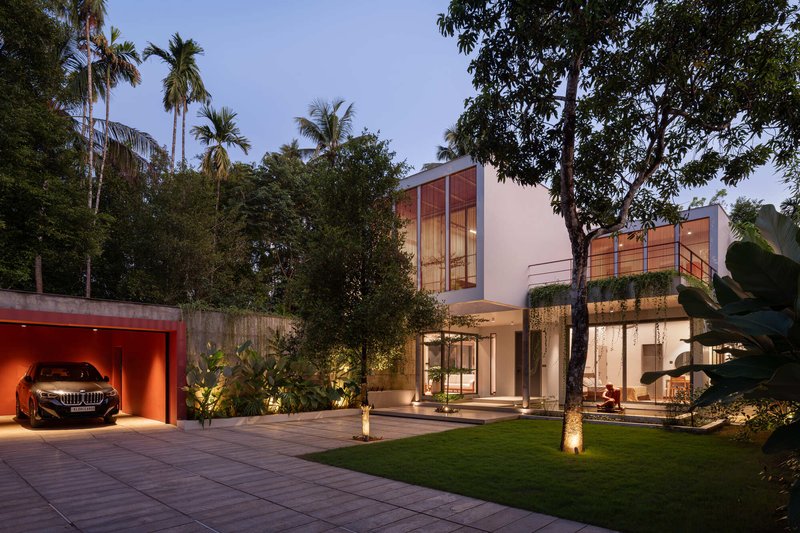 Dusk view of the residence from the courtyard showing illuminated interiors and timber louvred volumes above the lawn