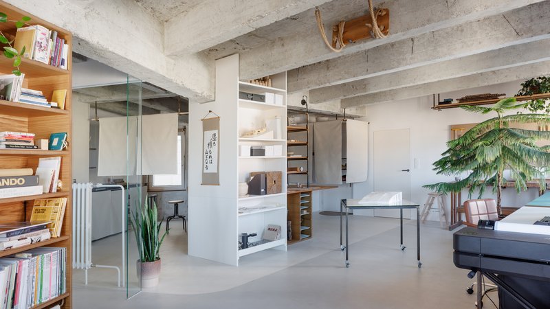 White storage unit with sliding barn door hardware and built-in shelving under concrete beams