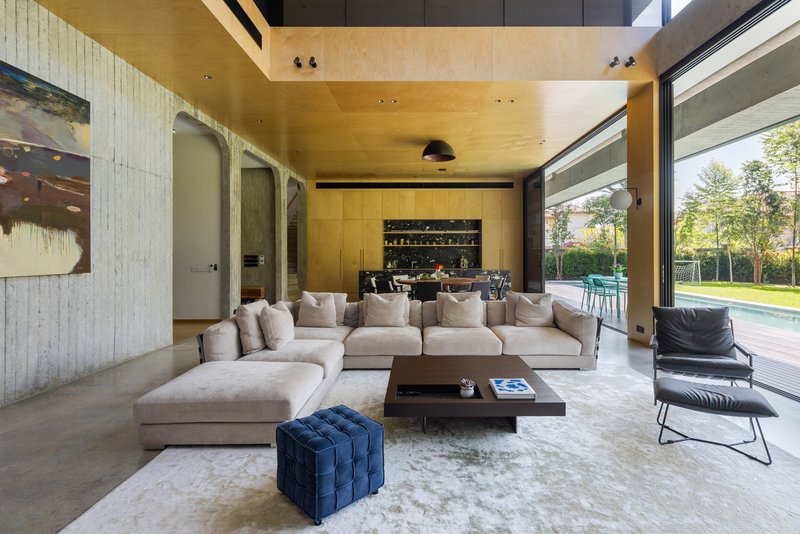 Living room with plywood ceiling and cabinetry opening to lawn and trees through sliding glass doors