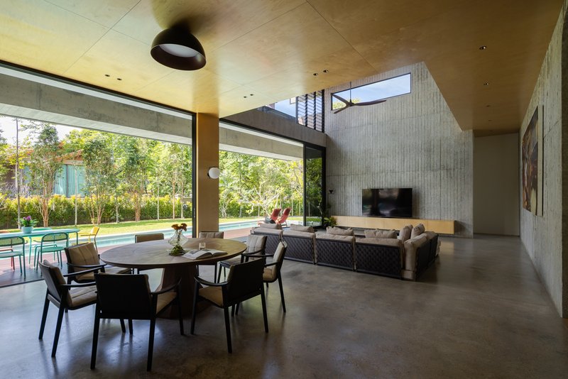 Open-plan living and dining space with polished concrete floor and clerestory light filtering through the garden