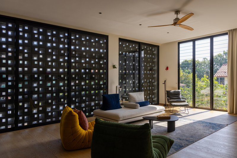 Living room with perforated black brick wall screens filtering daylight through square openings