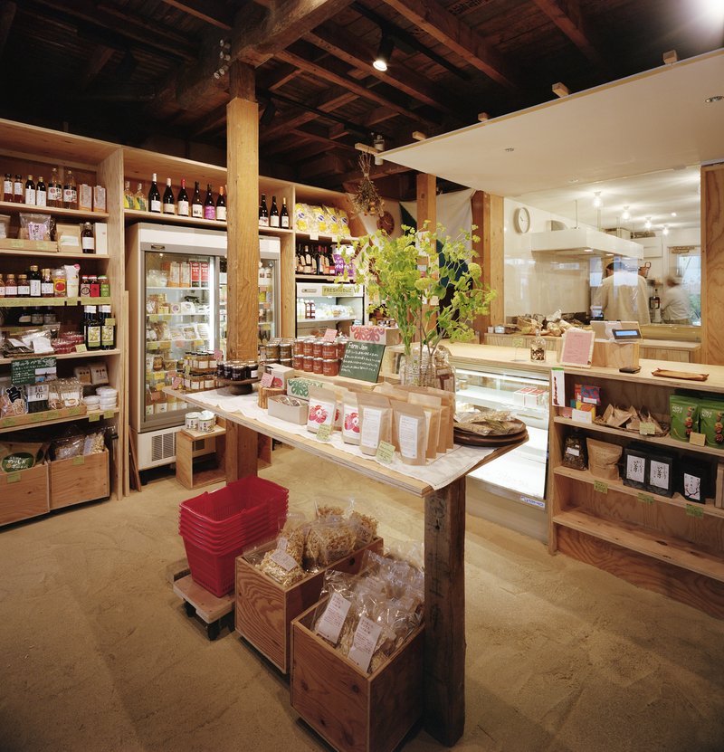 Retail space with exposed timber ceiling beams and plywood shelving displaying packaged goods