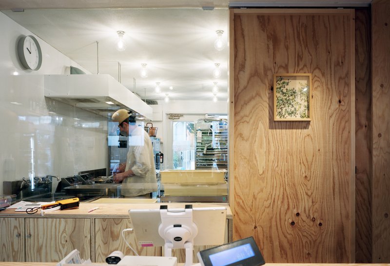 Kitchen counter with plywood panels and a framed floral artwork visible through glass