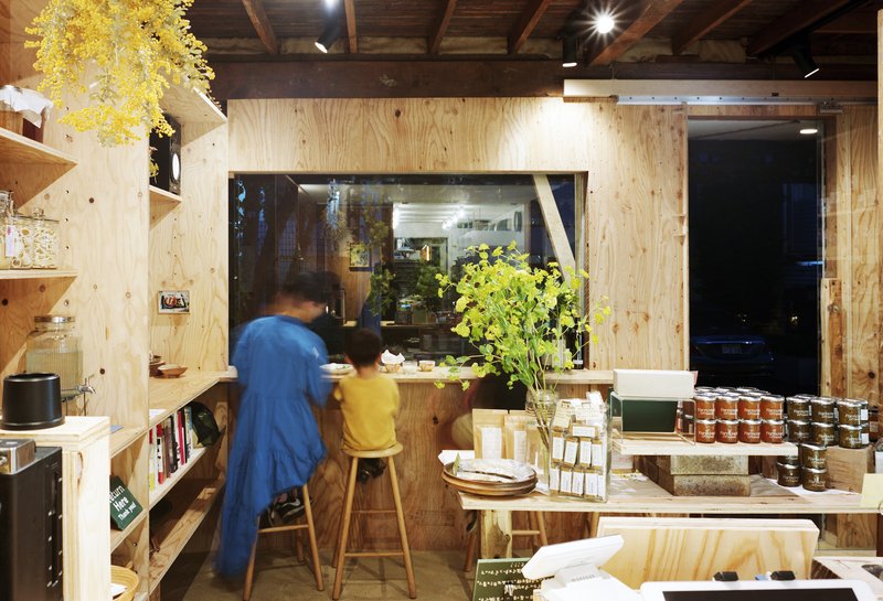 Shop interior with plywood counter and shelves as a person in blue moves past