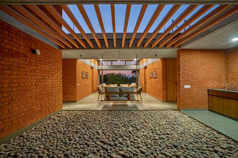 Interior courtyard with timber pergola, exposed rafters and pebbled floor at dusk