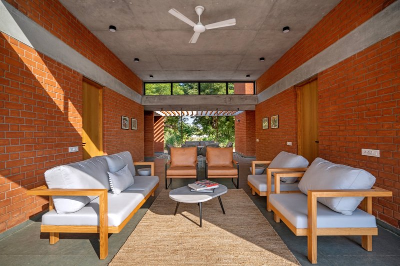 Living room with red brick walls framing a view through a slatted pergola to the landscape beyond