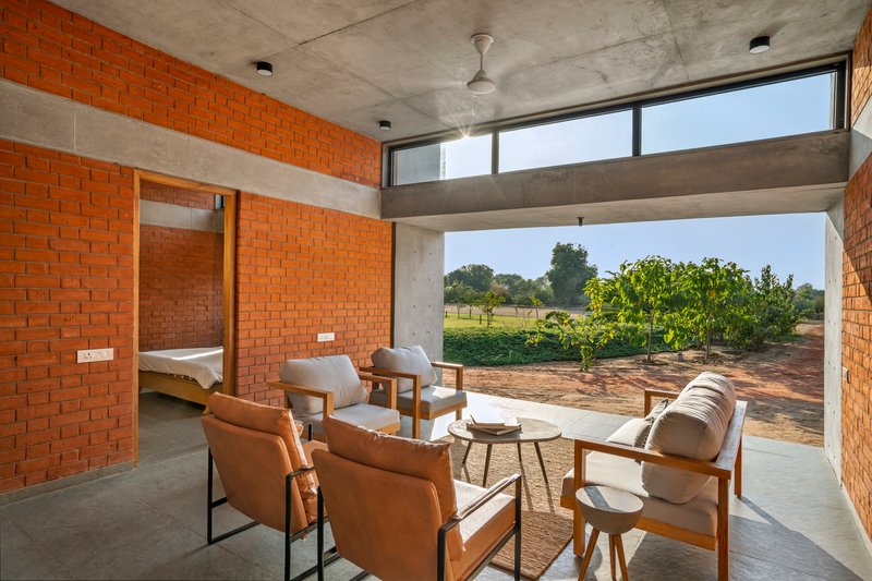 Interior seating area opening to agricultural fields through a wide concrete-framed aperture in morning light