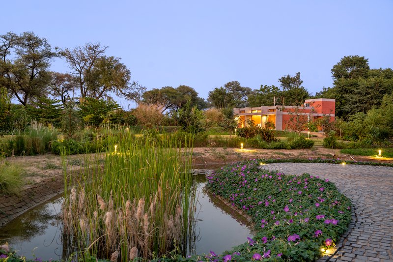 Garden pond with flowering plantings and paved terrace at twilight