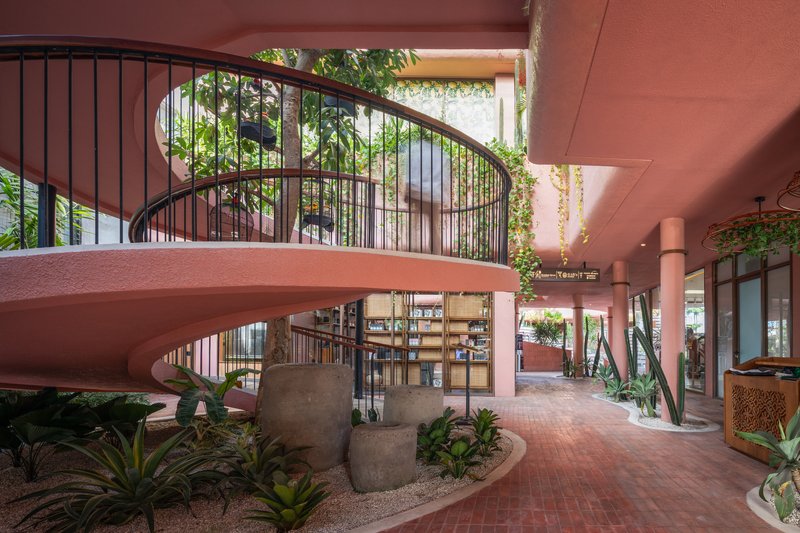 Curved staircase with black metal railings rising from the planted interior courtyard below