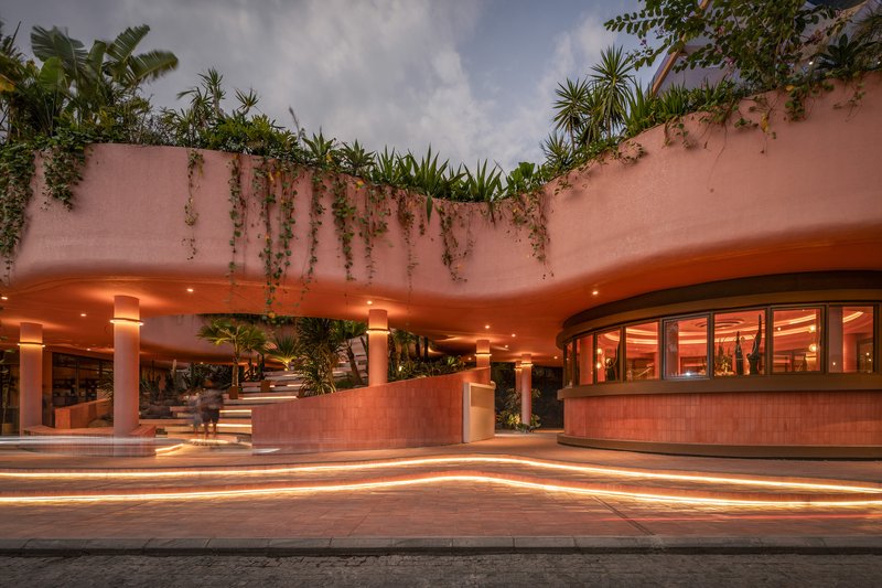 Covered portico with cylindrical columns and planted roof edge illuminated at dusk