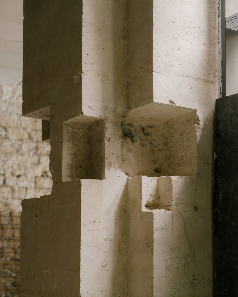 Concrete column base with formwork imprints and protruding rebars amid construction notes
