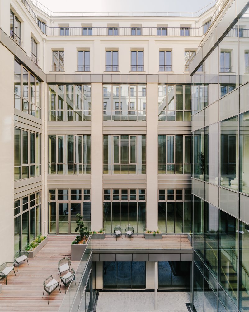 Interior courtyard with glass-enclosed volumes and diagonal structural bracing spanning between glazed facades