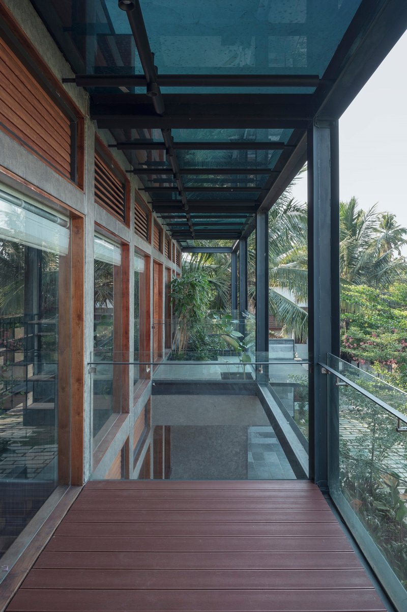 Covered timber deck walkway with steel frame and glass balustrade overlooking palms and greenery