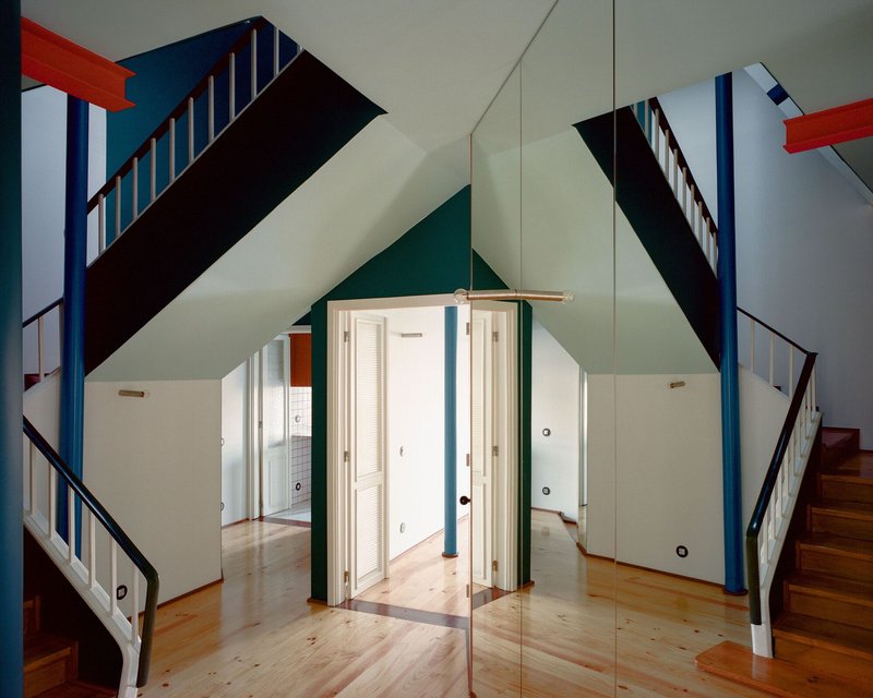 Stairwell intersection with blue and black painted railings, white louvered doors, and glass partition