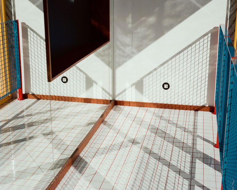 White grid tile floor receiving sharp diagonal shadows from an adjacent window