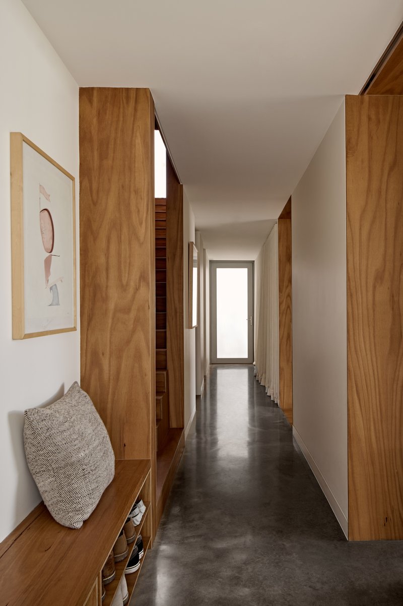 Corridor with timber cabinetry and polished concrete floor leading to a distant window