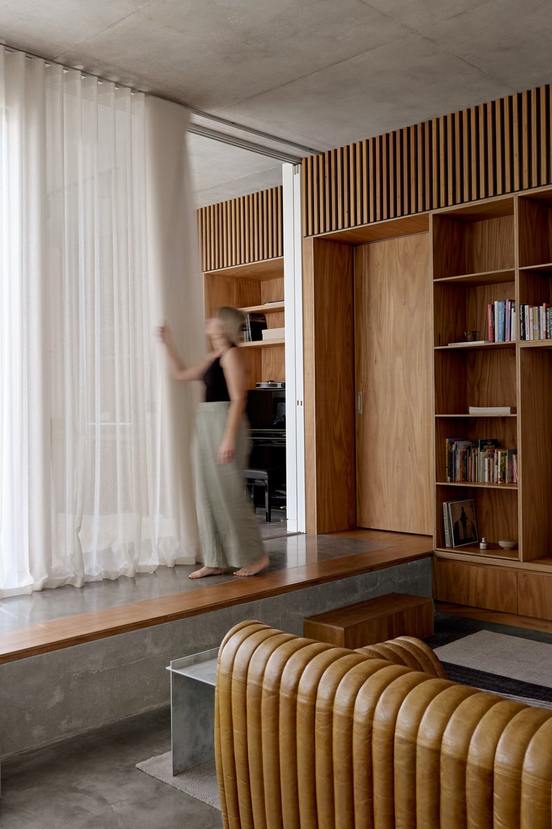 Same view showing a figure in motion passing through the curtained threshold between spaces