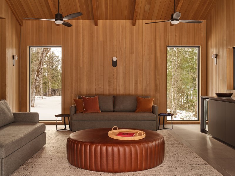 Seating area with timber ceiling, twin ceiling fans, and tall windows opening to snowy landscape