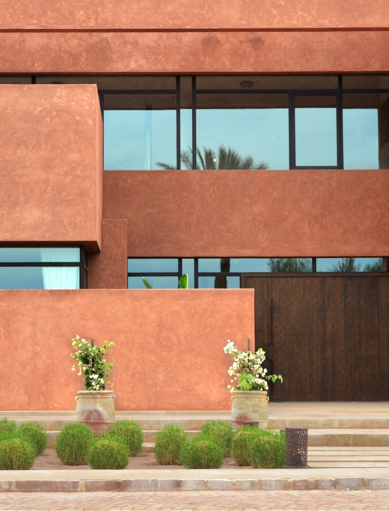Stacked terraces with horizontal ribbon windows reflecting palms and two planters flanking a timber screen wall