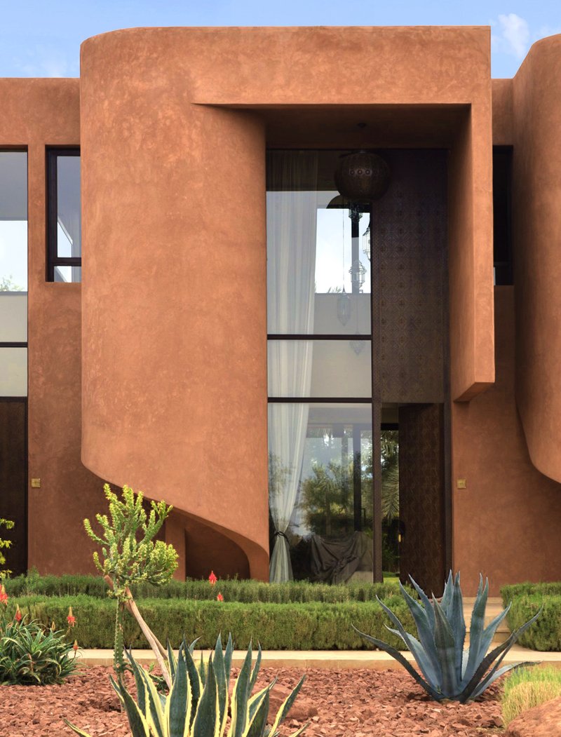 Curved stucco volume with floor-to-ceiling window overlooking a planted courtyard with agaves and aloes