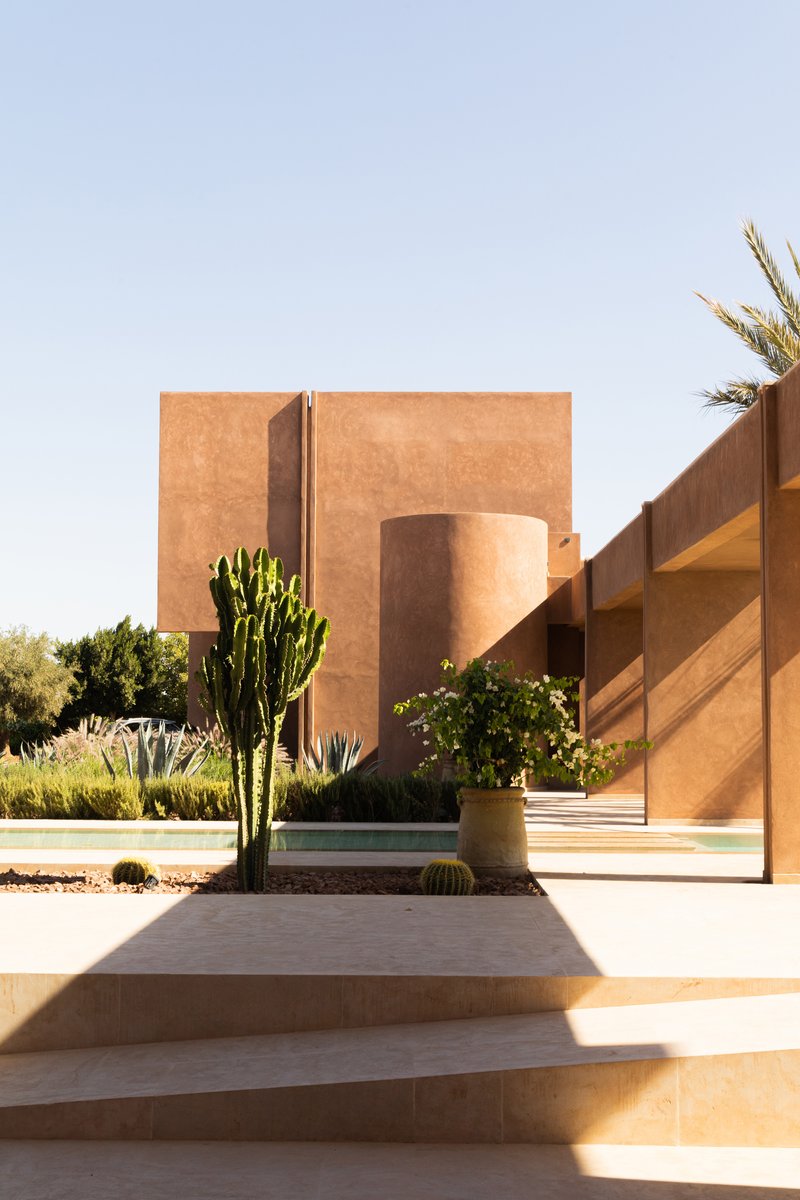 View of the rammed earth facade with planted cactus and agave in the desert landscape