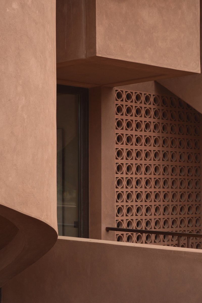 Terracotta breeze block screen beside a dark timber doorway beneath a plastered beam