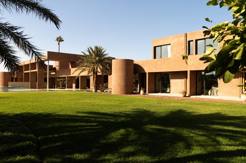 Garden view across the lawn showing cylindrical and cubic terracotta volumes framed by palm trees