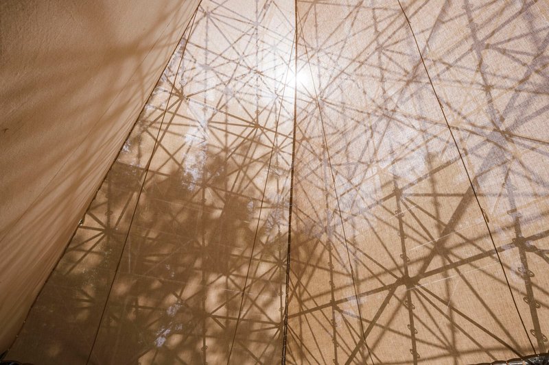 Translucent fabric wall with geometric structural shadows visible through the material in bright sunlight