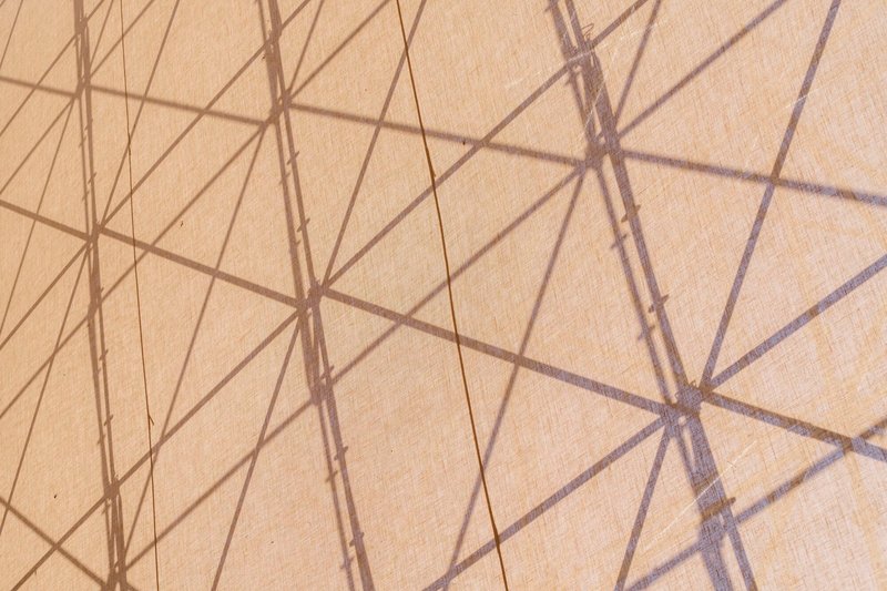 Detail of triangulated shadow pattern cast by structural framework onto a taut beige membrane