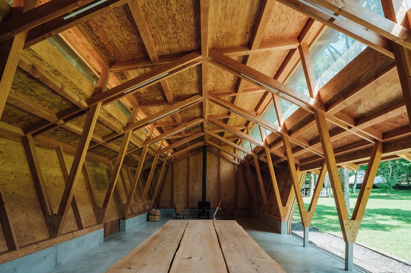 Interior view showing diagonal timber bracing and plywood ceiling panels with clerestory glazing above timber benches