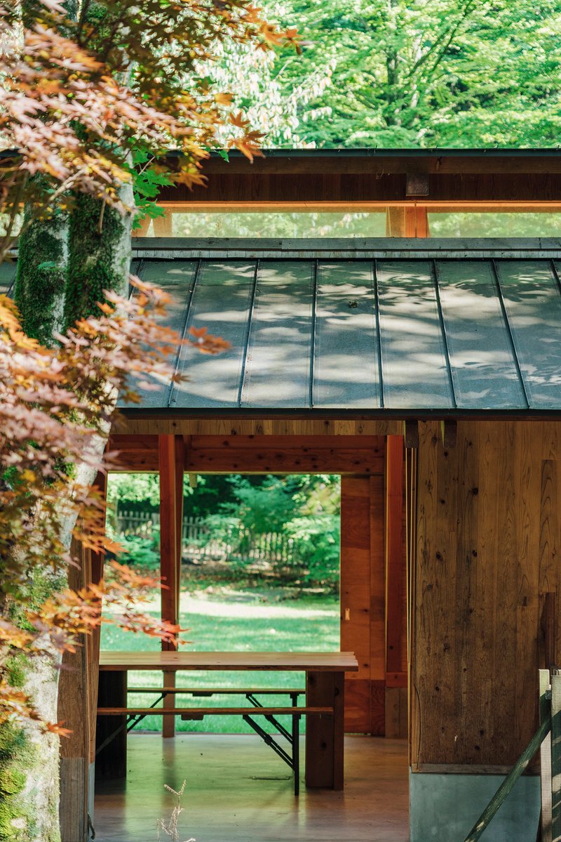 Exterior corner showing the metal standing seam roof overhang and timber columns framing views to the forest