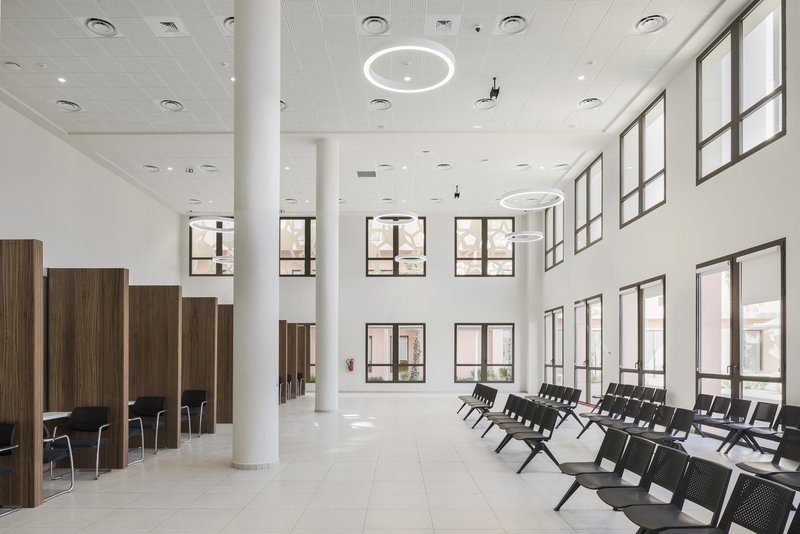 Double-height lobby with white columns, timber privacy screens and rows of seating