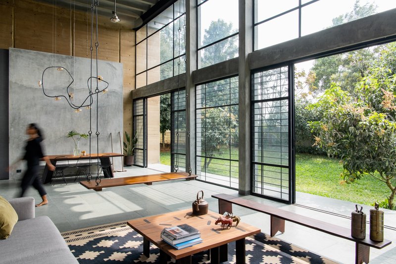Living space with steel-framed doors opening to garden while a person walks past the concrete wall