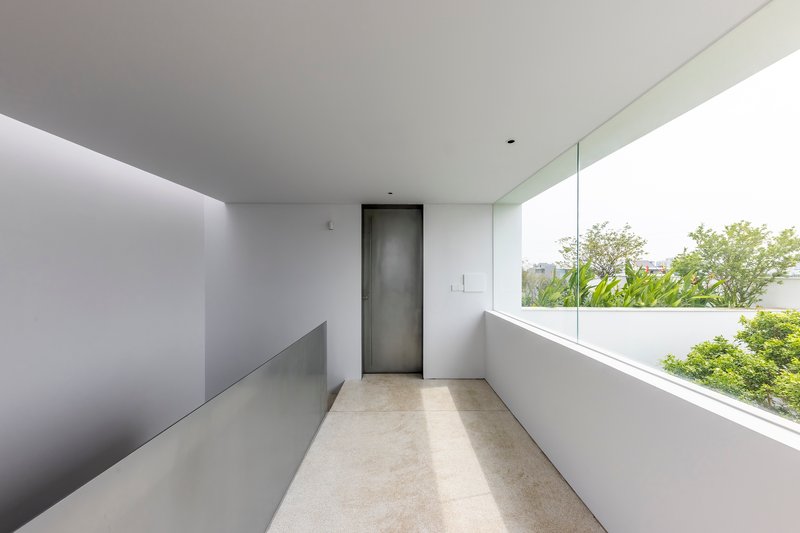 Upper-level corridor with terrazzo flooring and a horizontal window overlooking garden canopy